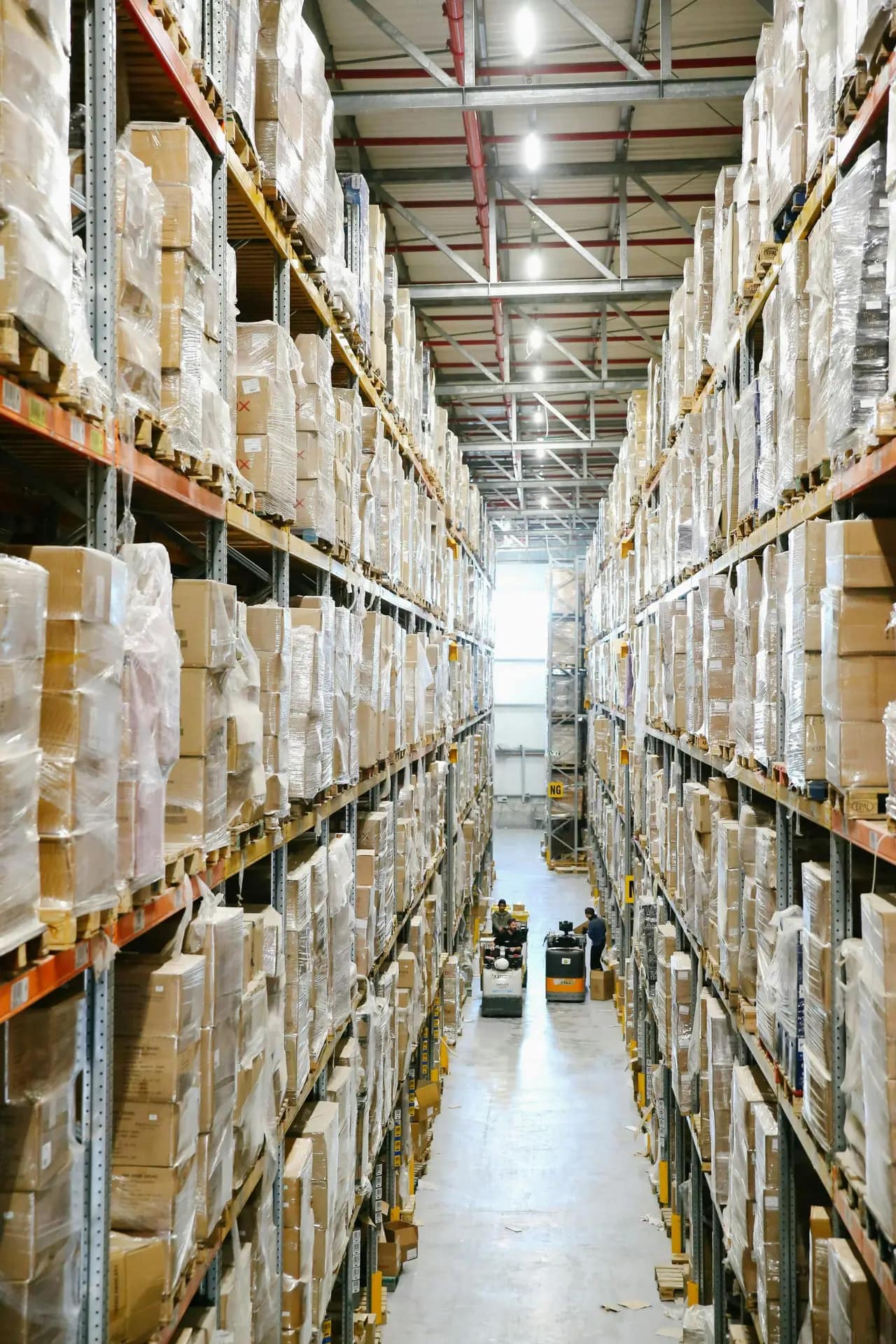 Services Spacious warehouse aisles lined with shelves stacked with boxes and packaging.