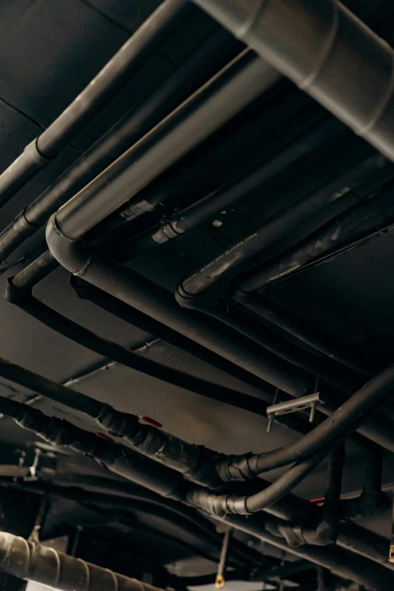 Services A vertical shot of industrial steel pipes and tubes in a dimly lit environment.