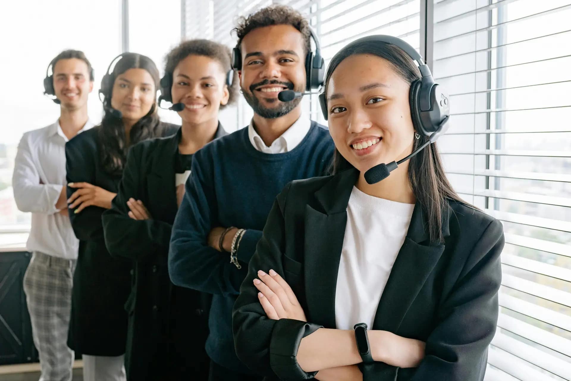 Services A diverse group of smiling call center agents in an office setting.