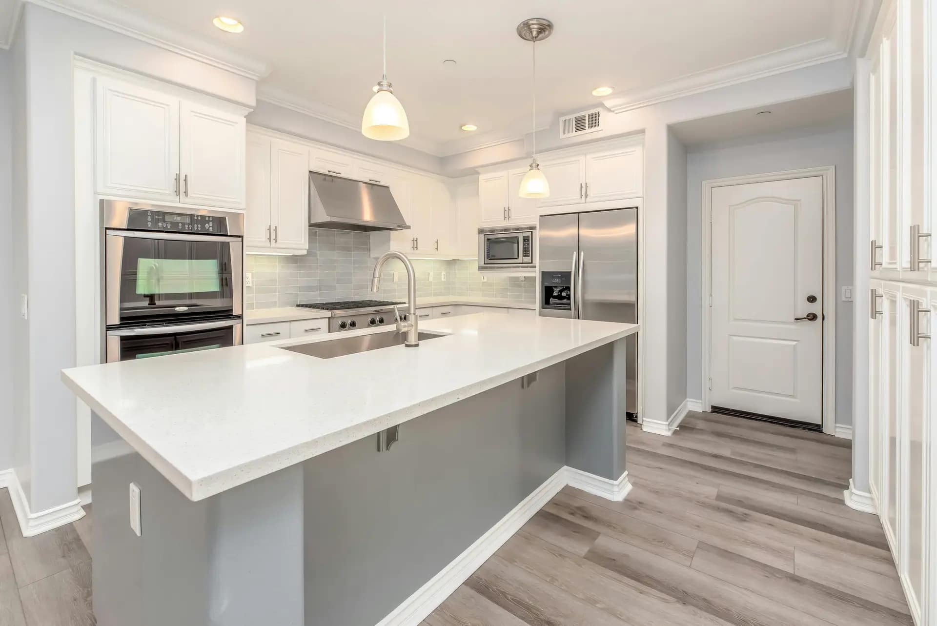 Services Modern kitchen interior featuring sleek white cabinetry and stainless steel appliances.